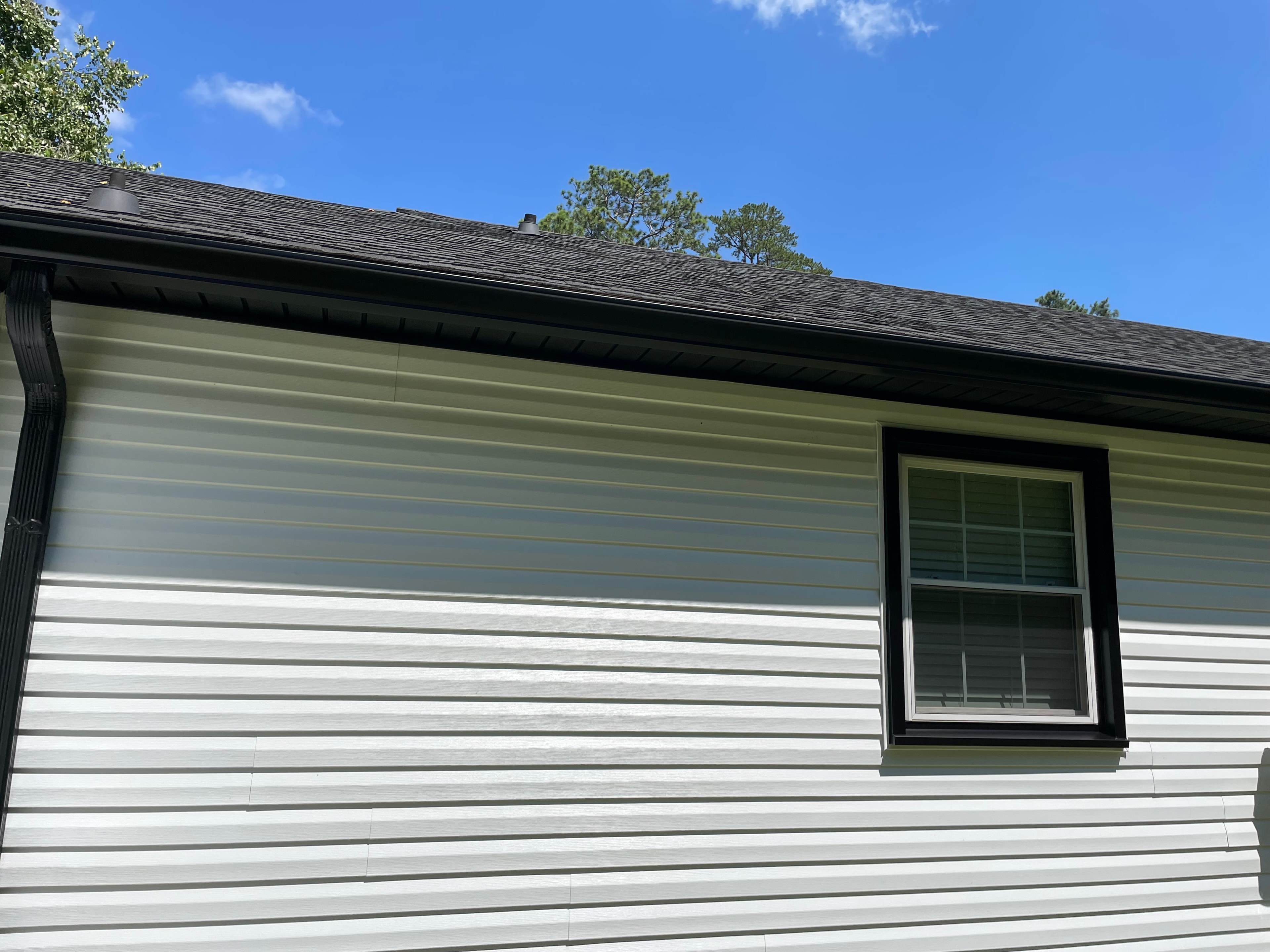 Black seamless gutters along roofline of home with siding